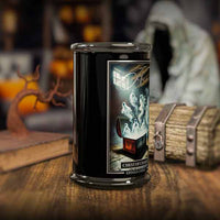 Candle in a black container with a ghostly design on a wooden surface