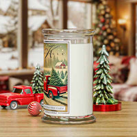 Decorative candle with a Christmas tree farm design on a table with festive decorations.