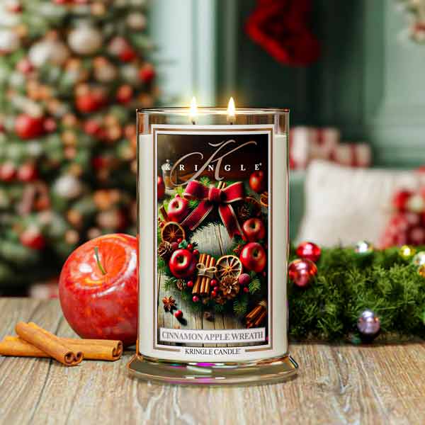 Kringle Candle with Christmas-themed label in front of a decorated Christmas tree.