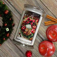 Kringle Candle packaging with Christmas-themed design on a wooden surface with apples and cinnamon sticks.