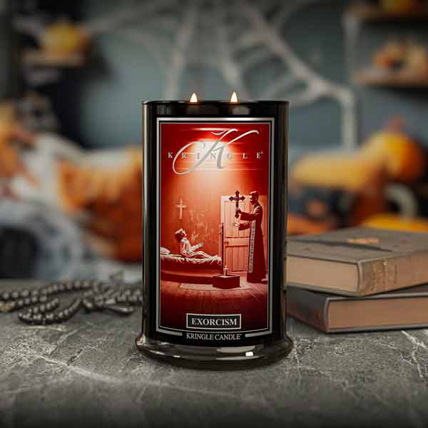 Kringle Candle with 'Exorcism' Halloween design on a dark surface with pumpkins and books in the background
