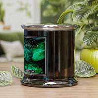 Black candle with green leaf design on label in a home setting