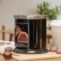 Black candle with a chocolate truffle design on a wooden surface