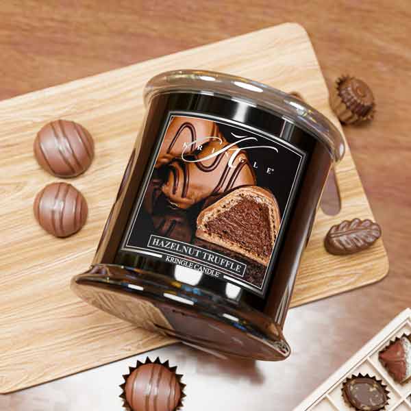 Jar of hazelnut truffle candle on a wooden board with chocolate truffles around