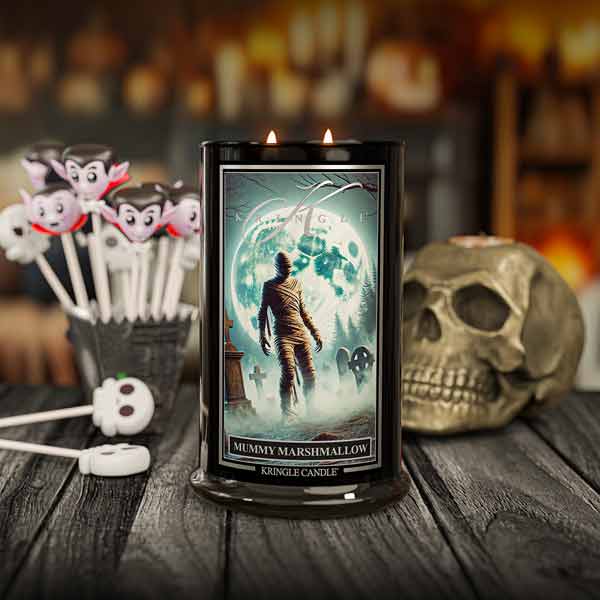 Kringle Candle mummy marshmallow candle with Halloween-themed decorations on a wooden surface.