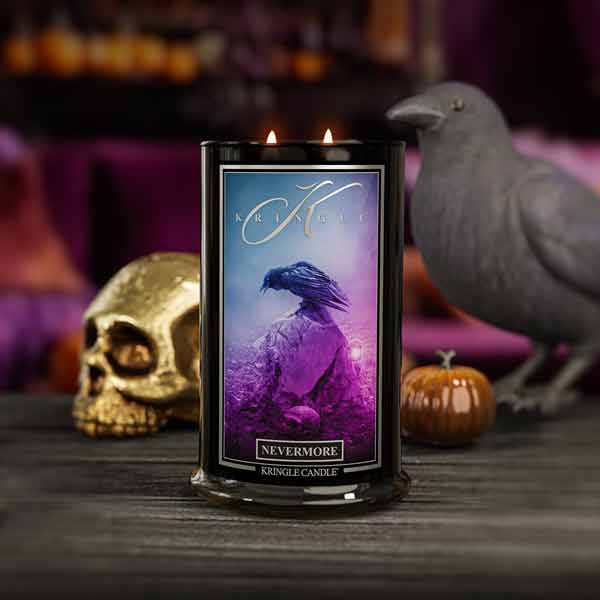 Kringle Candle with a purple label featuring a bird and text, surrounded by Halloween-themed decor including a skull and pumpkins.