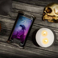 Kringle Candle 'Nevermore' candle with a skull and lit candle on a wooden surface
