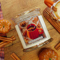 Kringle Candle pumpkin rum toddy candle with pumpkins and cinnamon sticks on a wooden surface