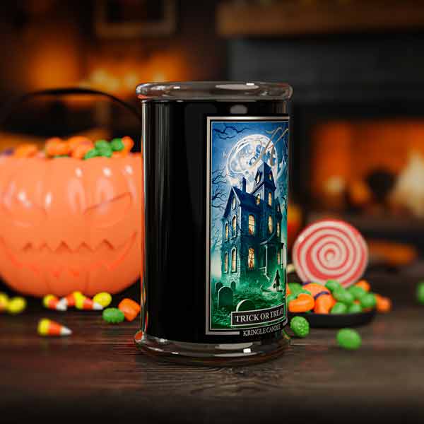 Halloween-themed candle with a haunted house label in front of decorative pumpkins and candy.
