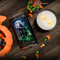 Halloween-themed candle with packaging and candy on a wooden surface