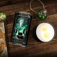 Scented candle packaging with a  Halloween label featuring witches around a cauldron on a wooden surface.