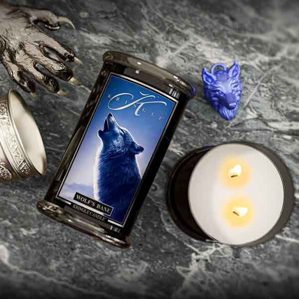 Wiccan candle with wolf design on a dark surface with a lit candle and wolf figurine.