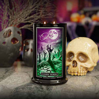 Candle with zombie design packaging on a Halloween-themed background with skull and pumpkins.