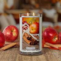 Kringle Candle Spiced Apple large lit candle with apples and cinnamon sticks on a wooden surface
