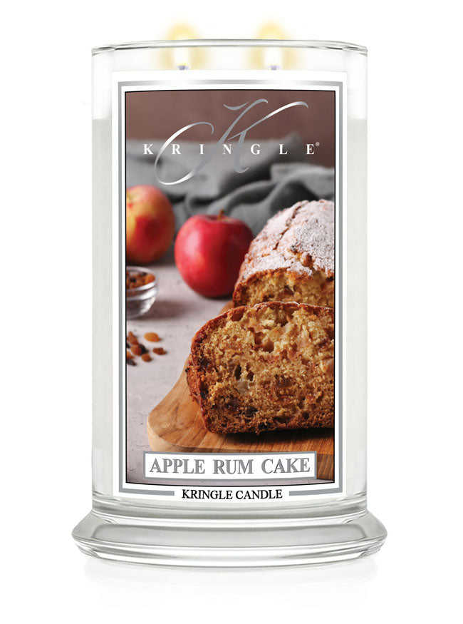 Lit large 2-wick candle with an image of sliced apple rum cake, apples, and nuts on the label.
