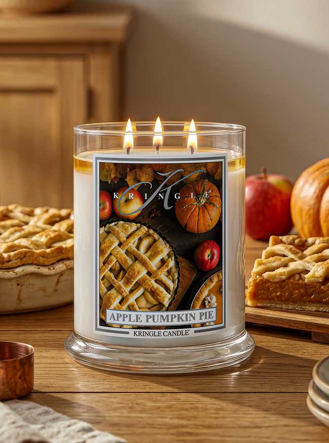 Kringle Candle with 'Apple Pumpkin Pie' label on a table with pie and pumpkins.