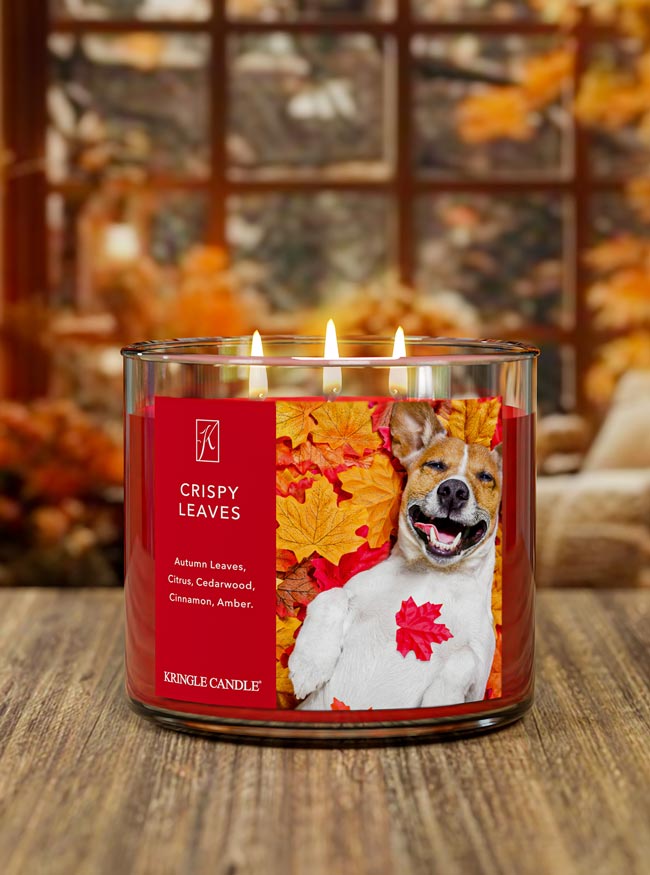 Kringle lit Candle with 'Crispy Leaves' label on a wood table with fall background