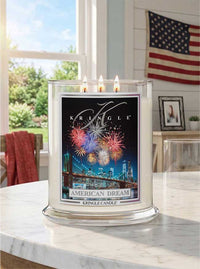 Kringle Candle with 'American Dream' fireworks design on a table in a bright room with an American flag.