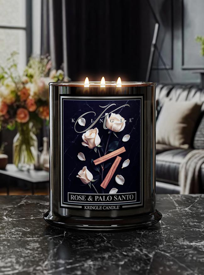 Kringle Candle with 'Rose & Palo Santo' fragrance on a dark surface with a blurred background