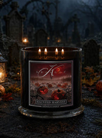 A  4-wick lit black glass jar candle with labeled 'Haunted Harvest' by Kringle Candle, set in a spooky graveyard scene with tombstones, lanterns, and autumn leaves.