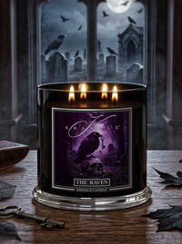 A black glass jar candle with four lit wicks and a purple gothic label reading 'The Raven' and 'Kringle Candle,' placed on a wooden table with a spooky graveyard scene in the background.