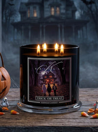 A black glass jar candle with four lit flames sits on a rustic wooden surface. The front label shows a haunted-house illustration with the text 'Kringle' and 'Trick or Treat'.