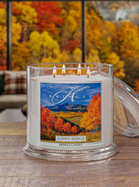 Kringle Candle with 'Aspen Ridge' label in front of autumn foliage