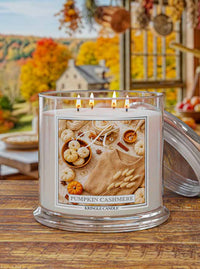 Kringle Candle Pumpkin Cashmere candle on a wooden surface with autumn decorations in the background