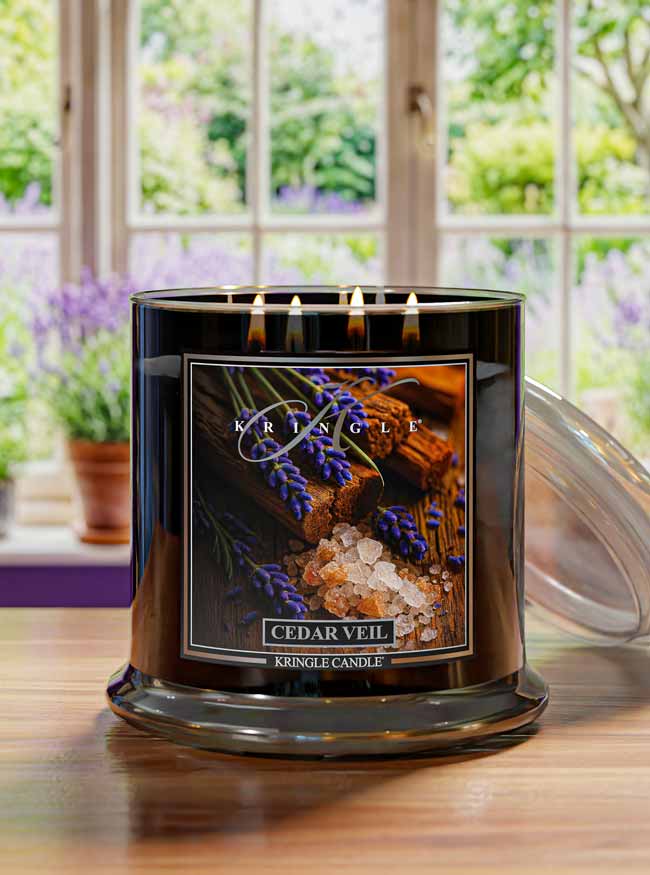 Kringle Candle in Cedar Veil with a scenic label in a room with large windows and plants.