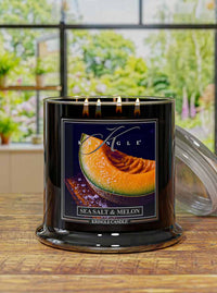 Kringle Candle with 'Sea Salt & Melon' label design on a wooden surface with a blurred outdoor background