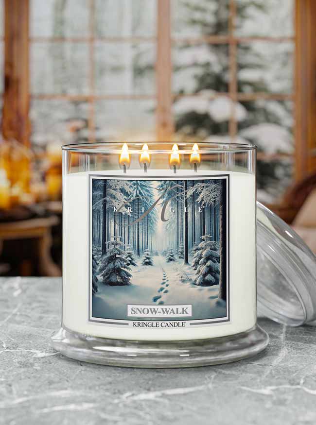 Kringle Candle 'Snow-Walk' candle with a winter forest design on a table.