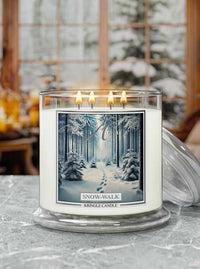 Kringle Candle 'Snow-Walk' candle with a winter forest design on a table.
