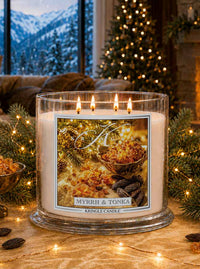 Myrrh & Tonka 4-wick lit candle jar by Kringle Candle in a living room setting with holiday tree and decor.