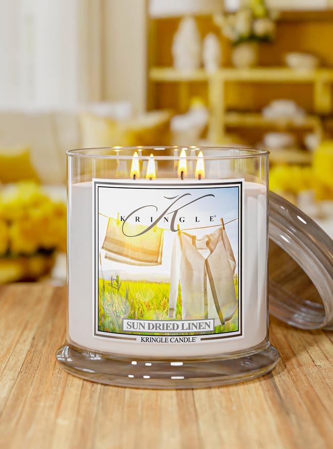 Kringle Candle in 'Sun Dried Linen' scent on a wooden surface with a blurred background