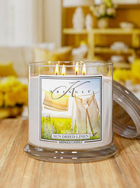 Kringle Candle in 'Sun Dried Linen' scent on a wooden surface with a blurred background