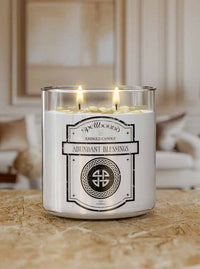 Lit Candle with a label reading 'Abundant Blessings' on a wooden surface.