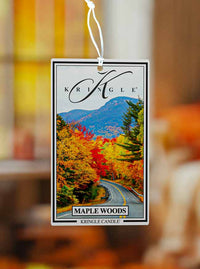 Kringle Candle Maple Woods air freshener with a scenic design of trees and mountains.