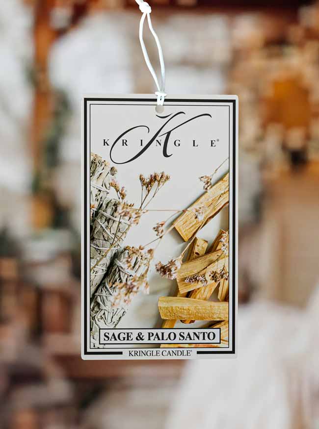 Kringle Candle Sage & Palo Santo air freshener tag against a blurred background