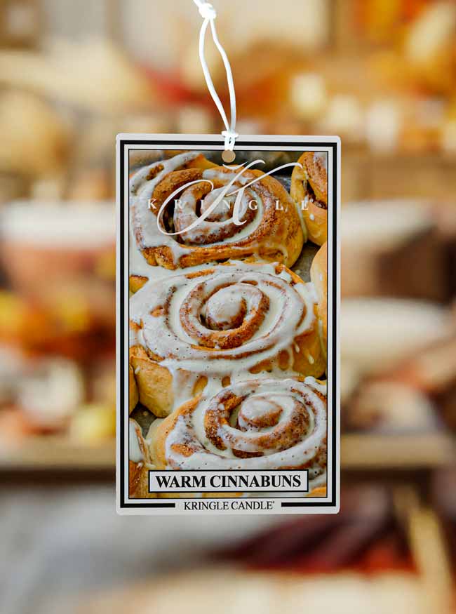 Kringle Candle cinnamon roll scented air freshener with blurred bakery background
