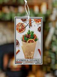 Kringle Candle air freshener tag with cypress and cinnamon scents on a blurred background