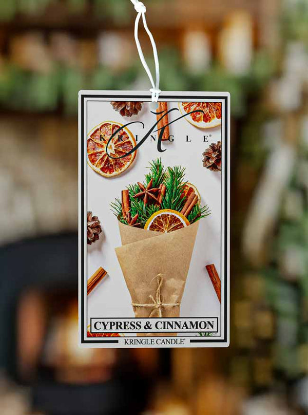 Kringle Candle air freshener tag with cypress and cinnamon scents on a blurred background