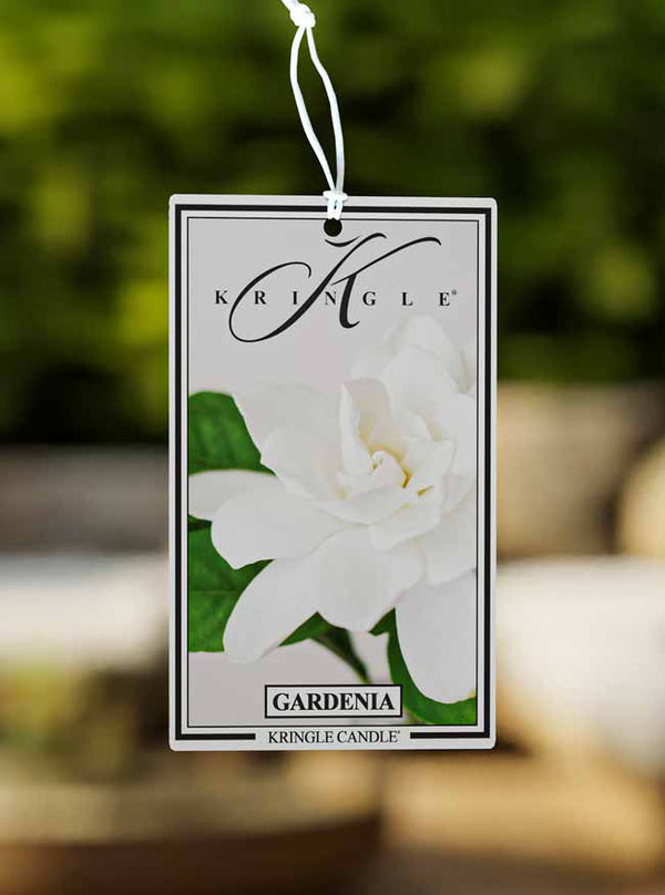 Kringle Candle Gardenia fragrance tag with a white flower on a blurred background