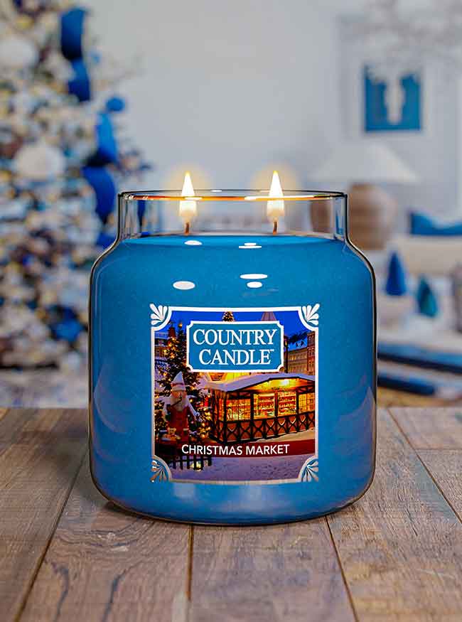 Blue Country Candle Christmas Market scented candle on a wooden surface with a festive background.