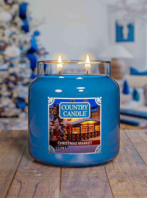 Blue Country Candle Christmas Market scented candle on a wooden surface with a festive background.