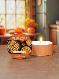 Kringle Candle Apple Pumpkin Pie candle and packaging on a table with a cozy indoor background.