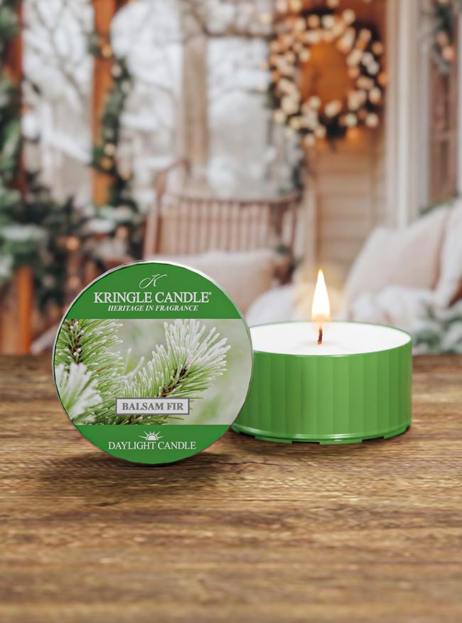Kringle Candle Balsam Fir candle on a wooden surface with a festive background