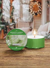 Kringle Candle Balsam Fir candle on a wooden surface with a festive background
