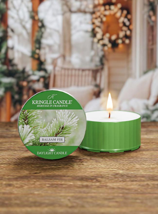 Kringle Candle Balsam Fir candle on a wooden surface with a festive background