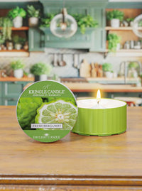 Green candle with a Kringle Candle label on a wooden surface, with a kitchen in the background.