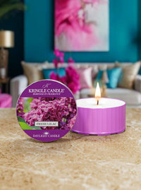 Kringle Candle Fresh Lilac candle on a table with a blurred living room background